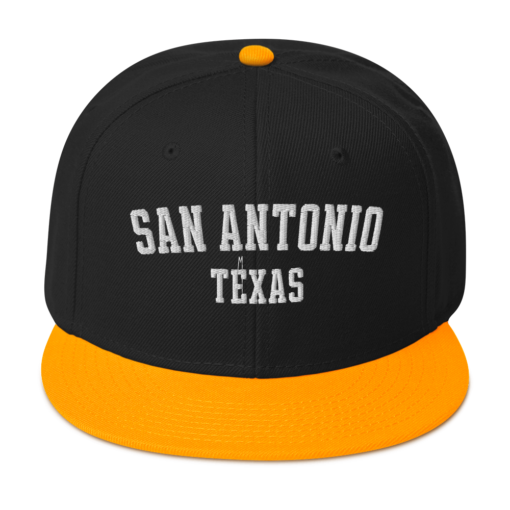 A black and gold snapback cap with the words "San Antonio, Texas".