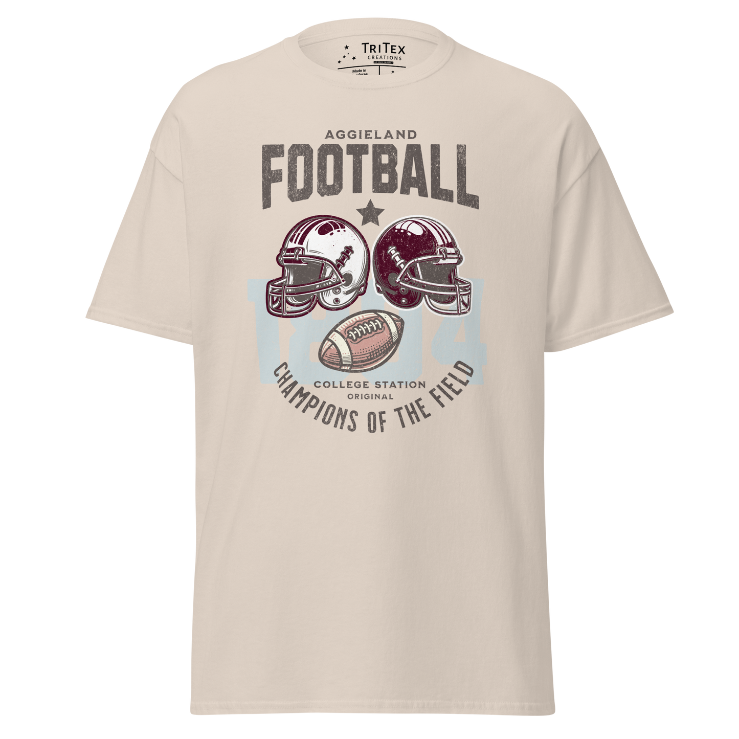 A natural-colored t-shirt featuring football helmets and a football with the text "Aggieland Football College Station original Champions of the field"