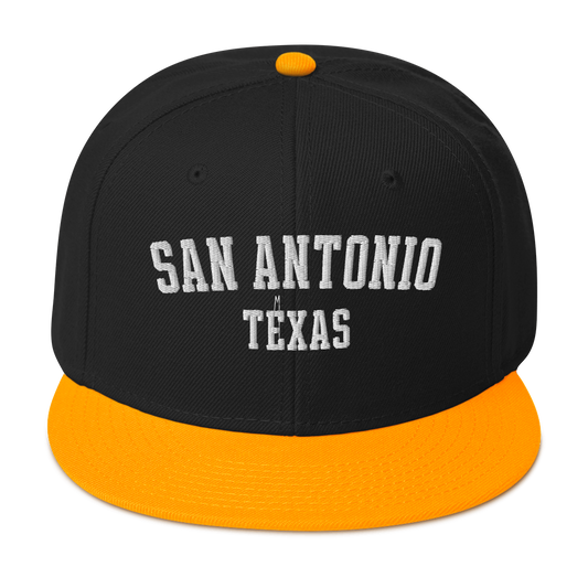 A black and gold snapback cap with the words "San Antonio, Texas".