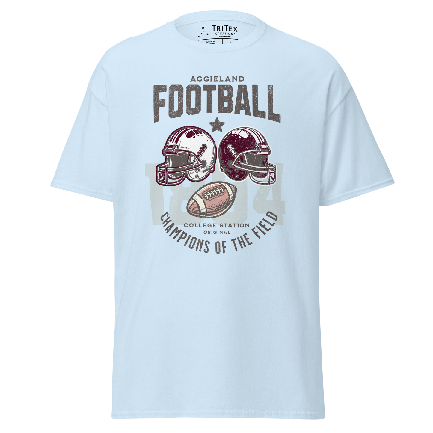 A light blue t-shirt featuring football helmets and a football with the text "Aggieland Football College Station original Champions of the field"