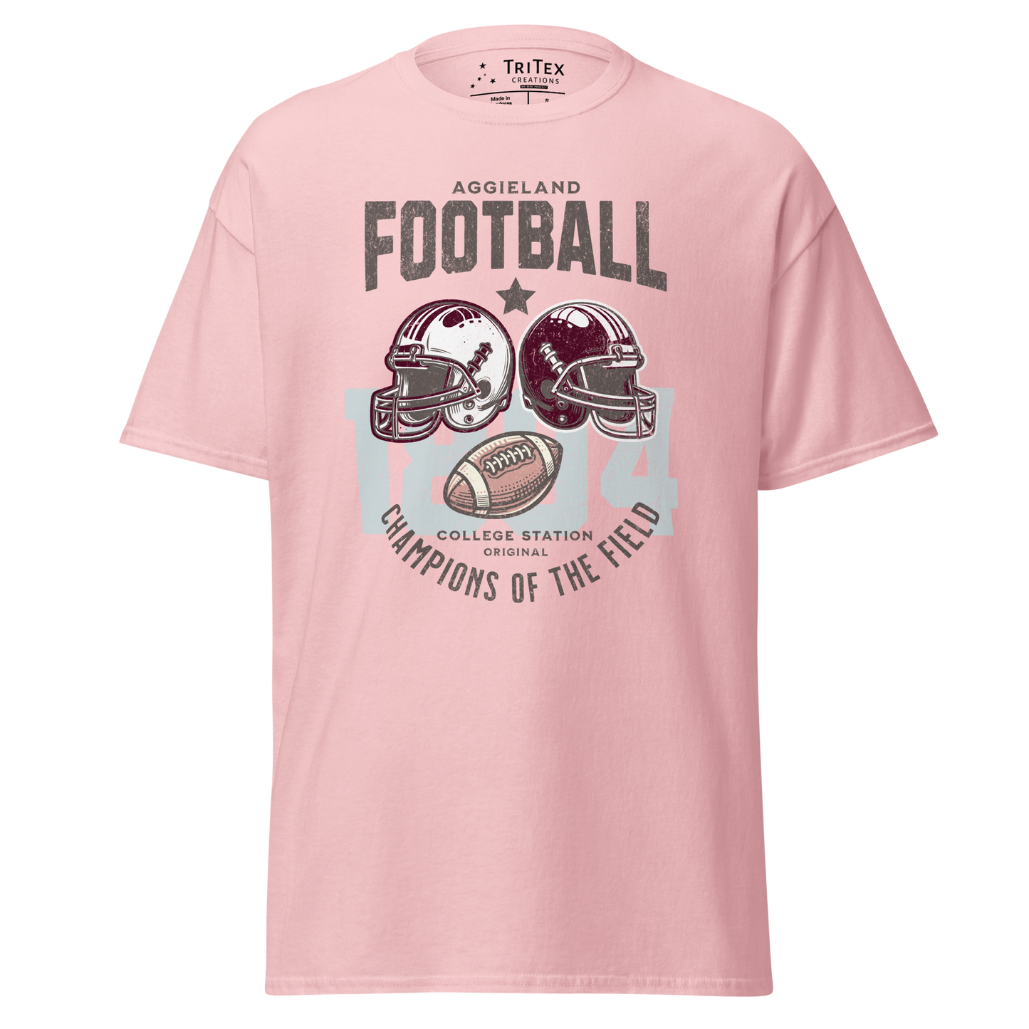 A light pink t-shirt featuring football helmets and a football with the text "Aggieland Football College Station original Champions of the field"