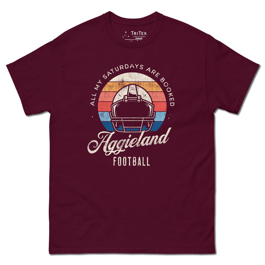 A maroon t-shirt featuring a football helmet and the words "All my Saturdays are booked Aggieland Football".