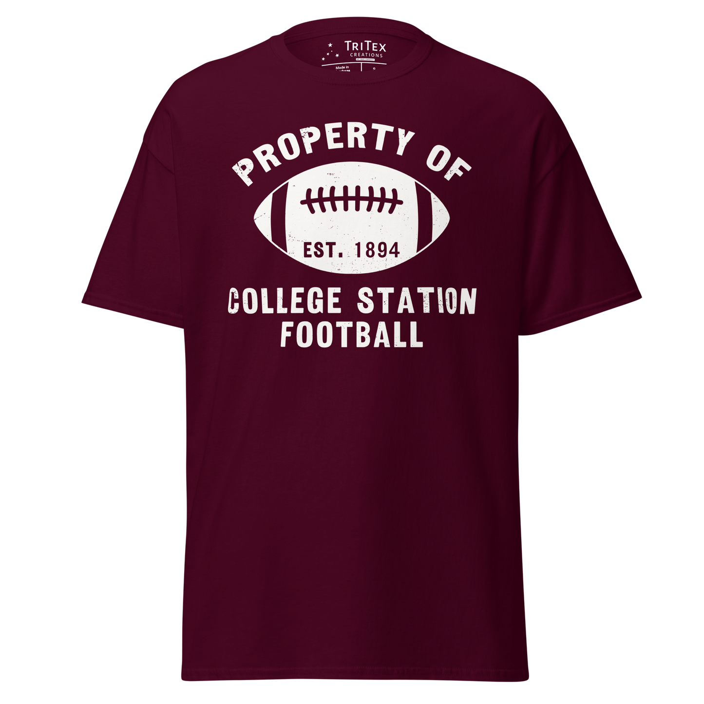 A maroon t-shirt featuring a silhouette of a football with the words "Property of College Station football. Est. 1894".