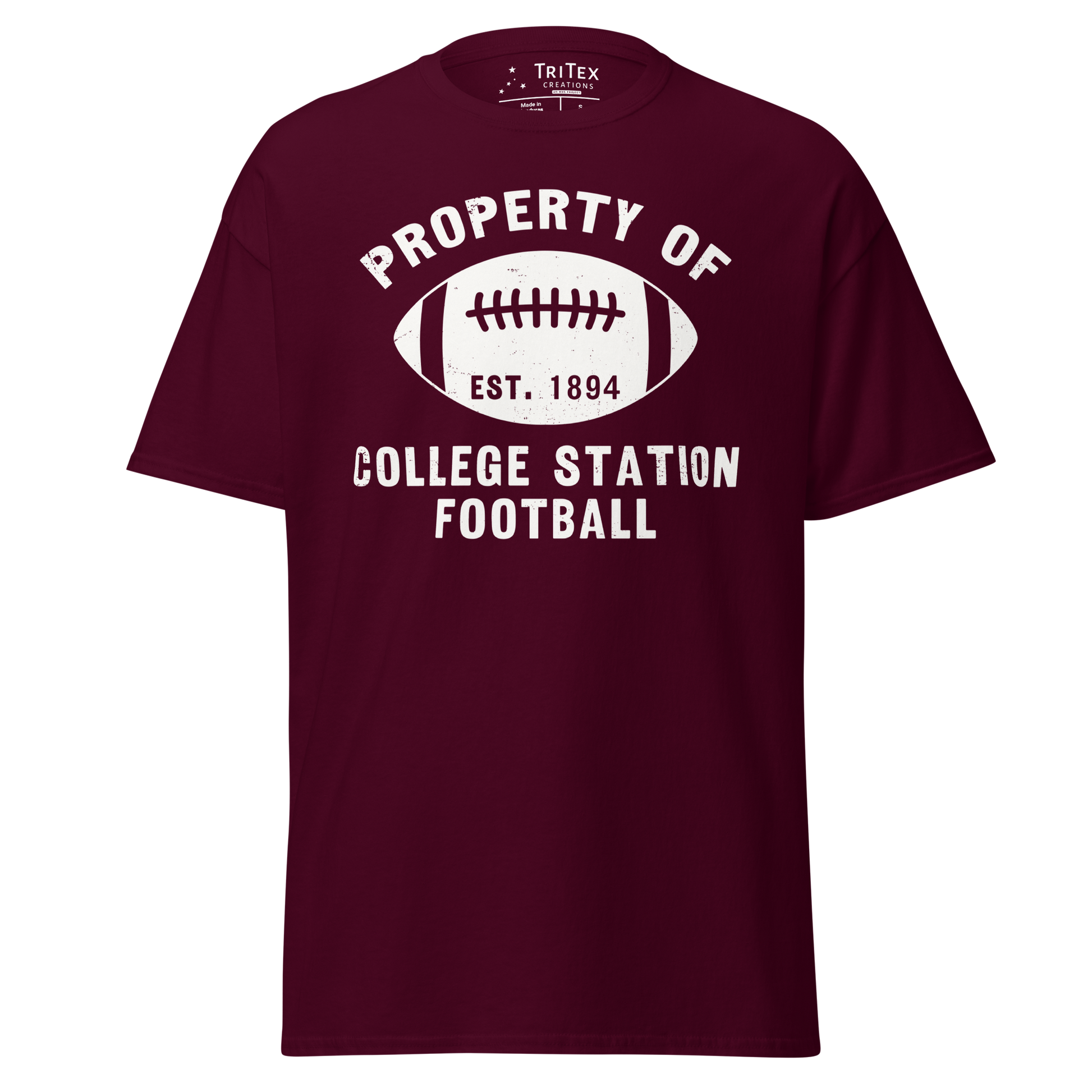 A maroon t-shirt featuring a silhouette of a football with the words "Property of College Station football. Est. 1894".