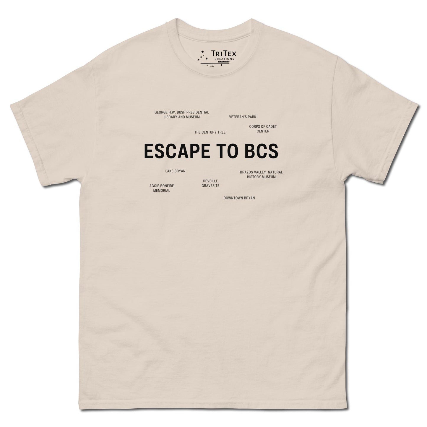 A natural-colored t-shirt which reads "Escape To BCS" in big, bold text with smaller text elements naming Bryan and College Station's landmarks.