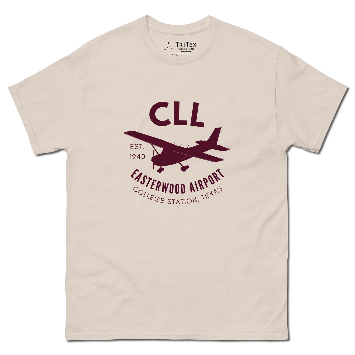 A natural-colored t-shirt featuring a silhouette of a Cessna airplane with the words "CLL Est. 1940 Easterwood Airport College Station, Texas".