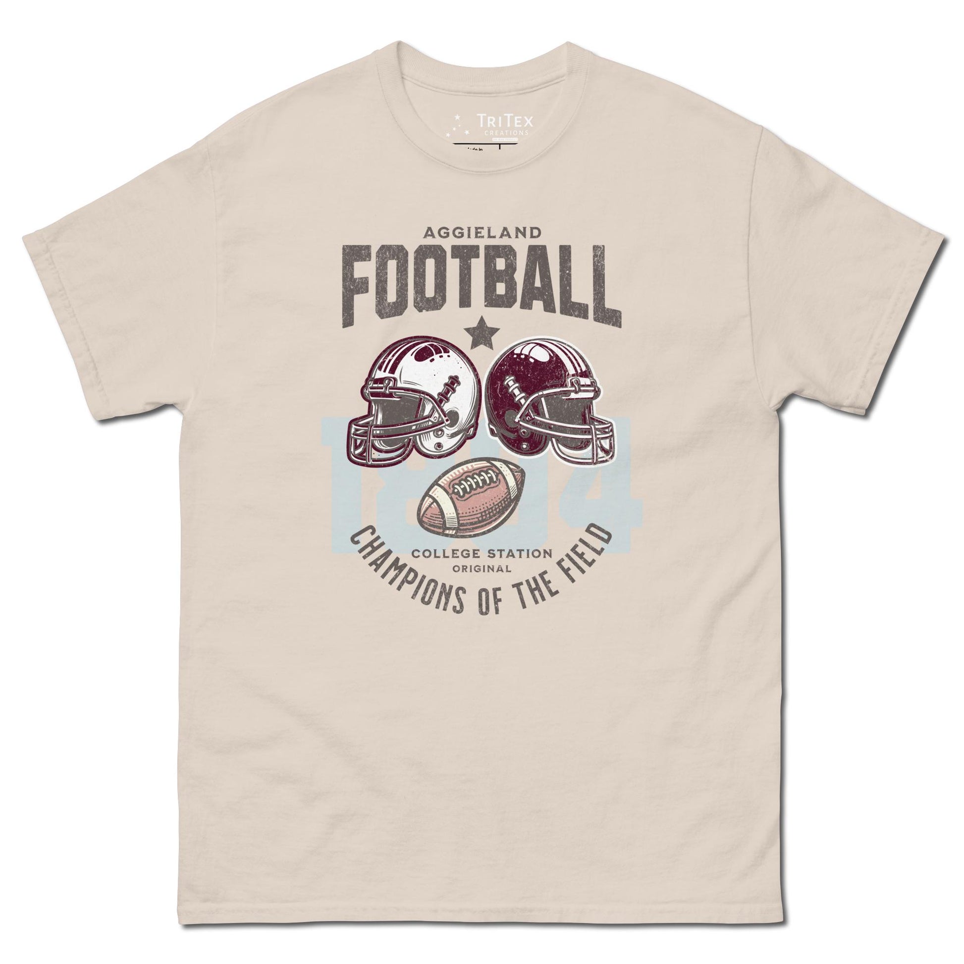 A natural-colored t-shirt featuring football helmets and a football with the text "Aggieland Football College Station original Champions of the field"