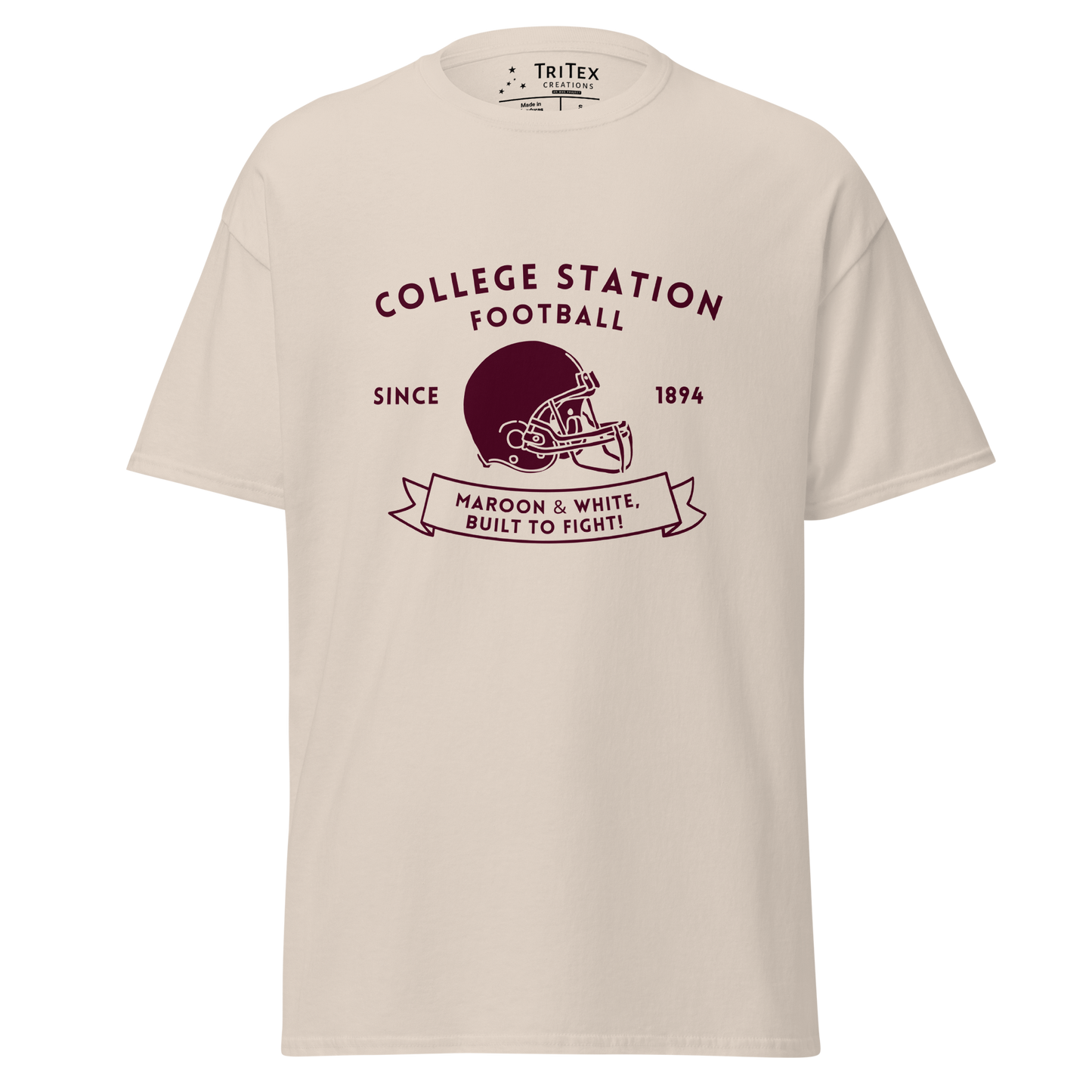 A natural-colored t-shirt with the text "College Station football since 1894 Maroon & White, Built to fight!" featuring an image of a football helmet.