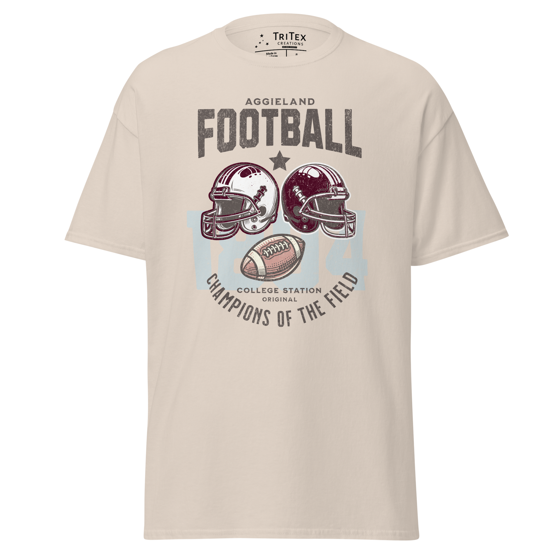 A natural-colored t-shirt featuring football helmets and a football with the text "Aggieland Football College Station original Champions of the field"