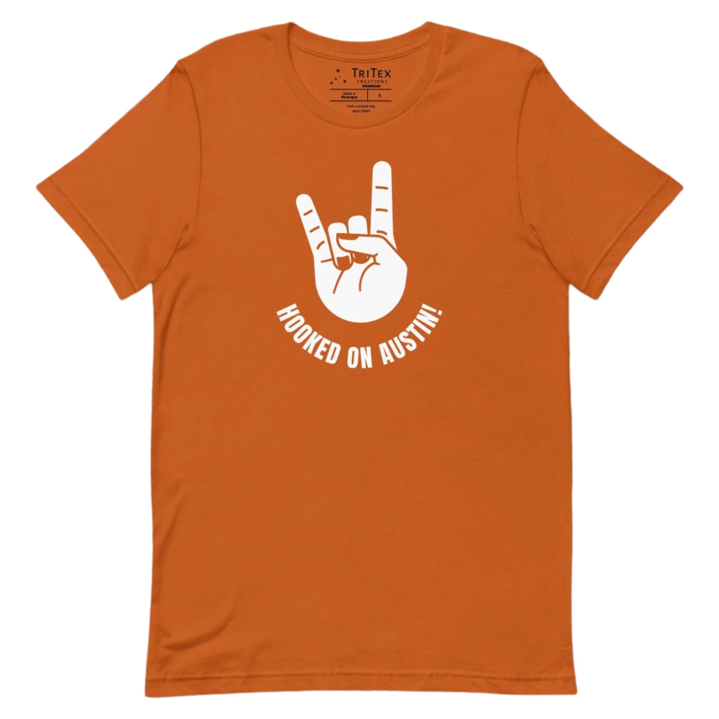 An autumn-colored t-shirt with a picture of a hand showing "devils horns" with the words "Hooked on Austin!".