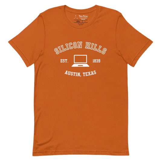 An autumn-colored t-shirt featuring a graphic image of a laptop with the words "Silicon Hills Est. 1839 Austin, Texas".