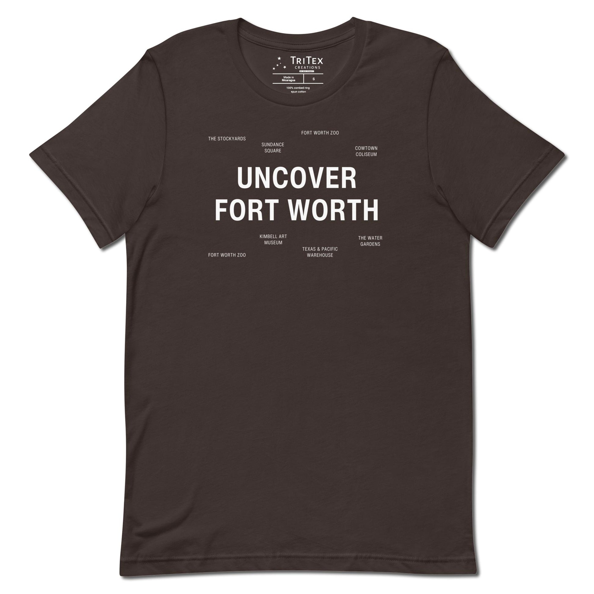 A brown t-shirt which reads "Uncover Fort Worth" in big, bold text with smaller text elements naming Fort Worth landmarks.