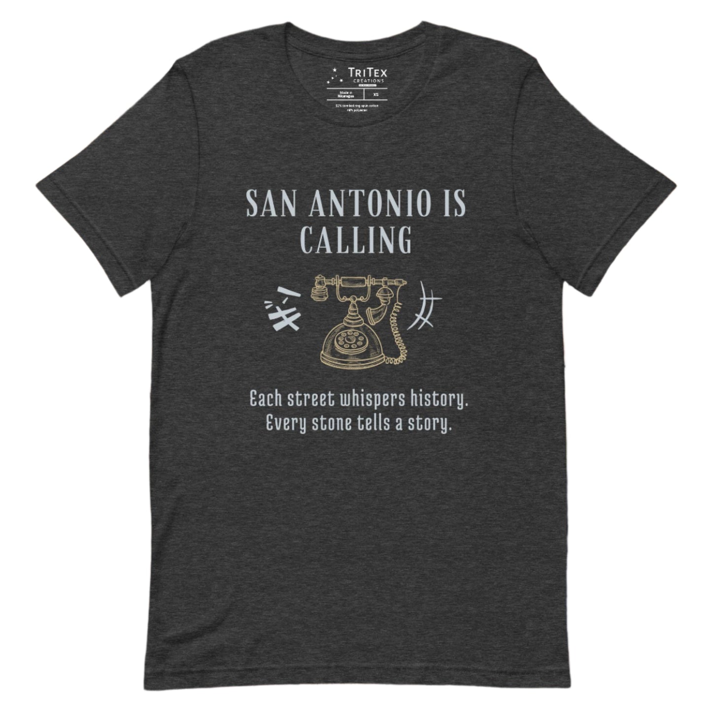 A dark gray heather t-shirt featuring a graphic image of a vintage rotary phone with the text "San Antonio is calling. Each street whispers history. Every stone tells a story."