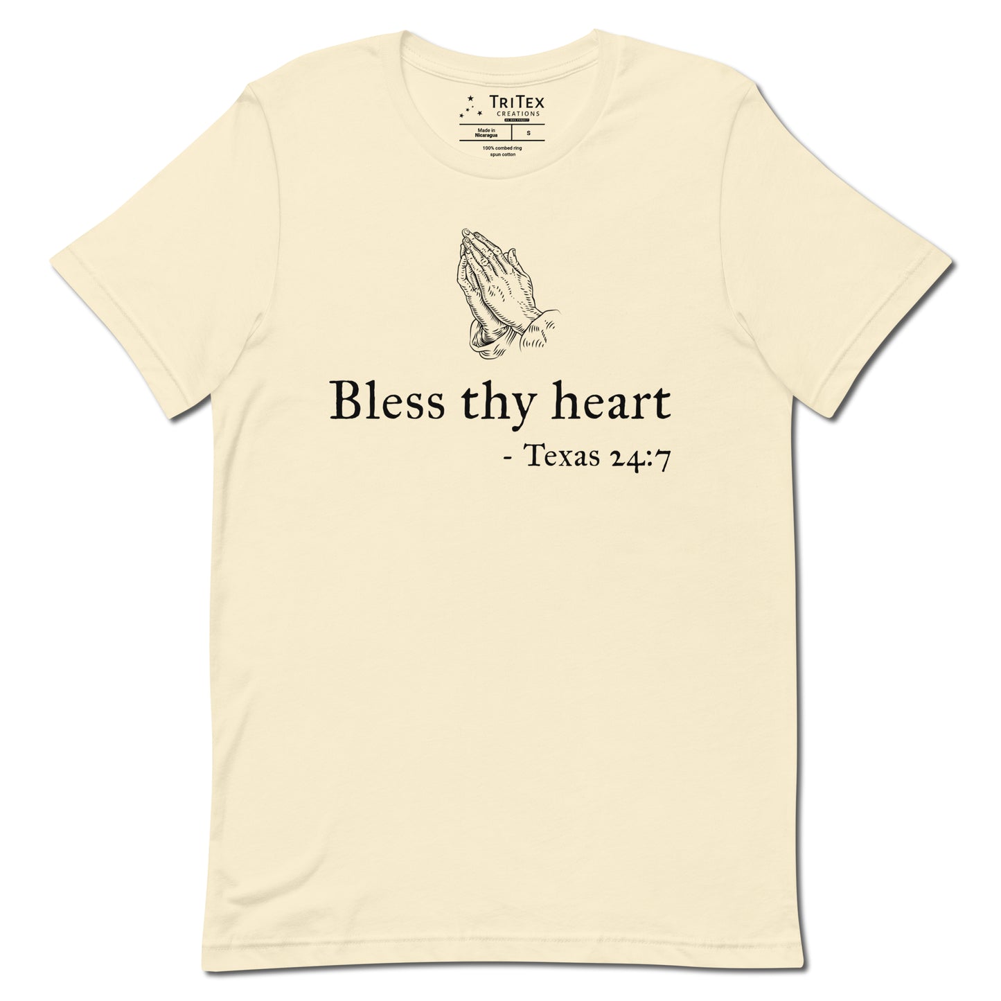 A natural-colored t-shirt featuring a vintage illustration of hands clasped in prayer with the words "Bless thy heart - Texas 24:7"