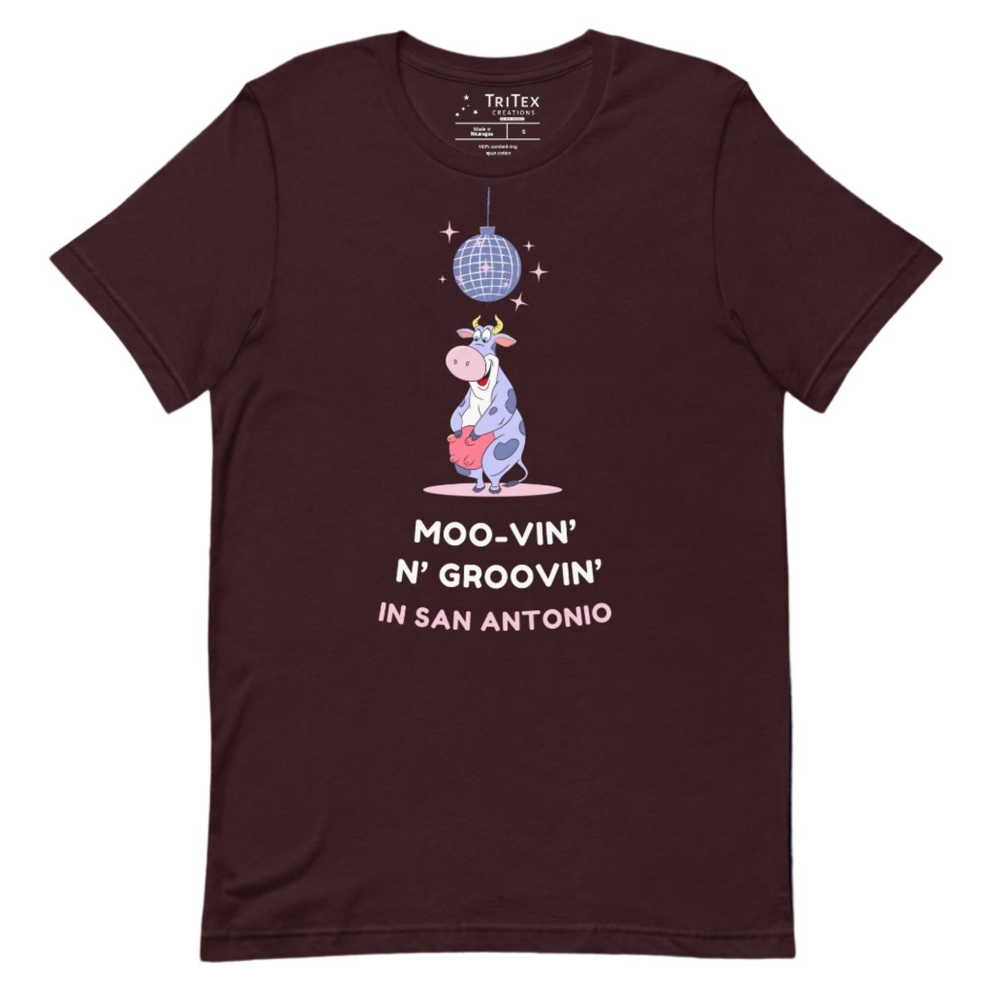 An oxblood black t-shirt with a cartoon cow standing under a sparkling disco ball with the the text "Moo-vin' n' groovin' in San Antonio".