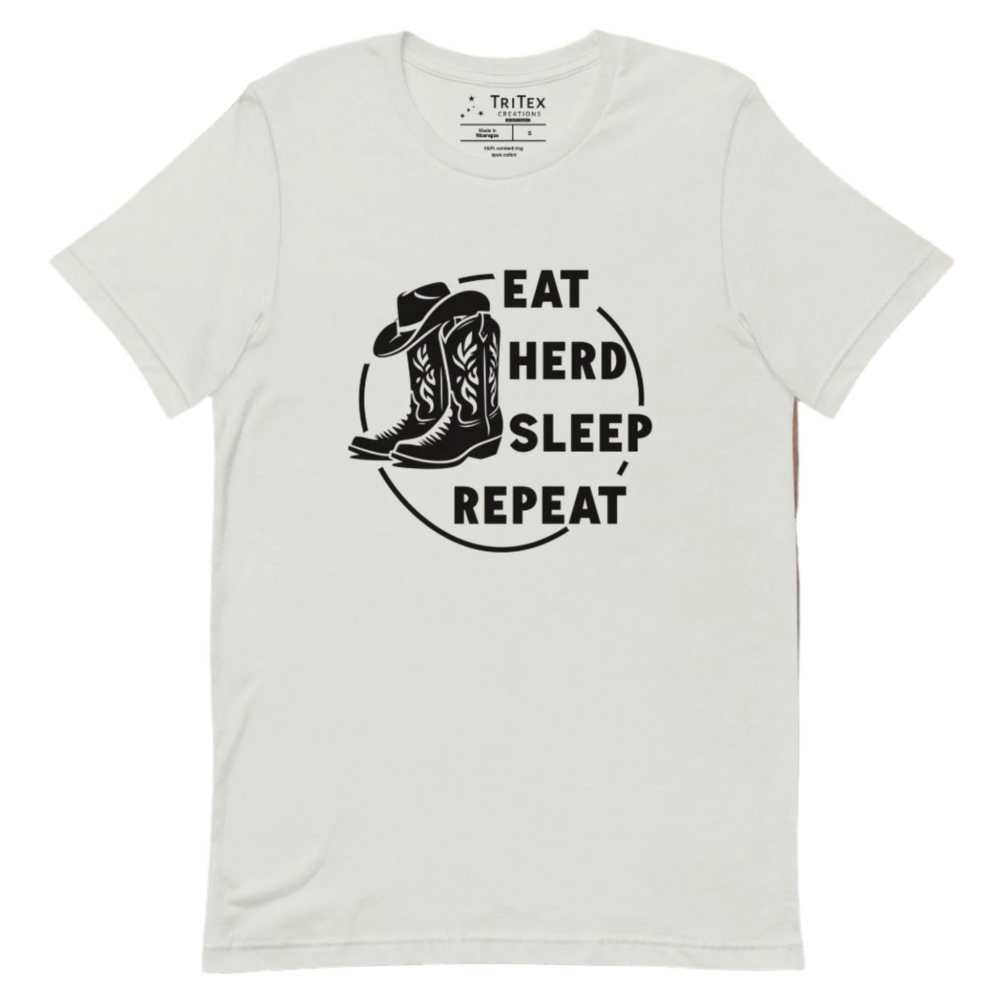 A silver t-shirt featuring boots and a cowboy hat with the words "Eat, herd, sleep, repeat".