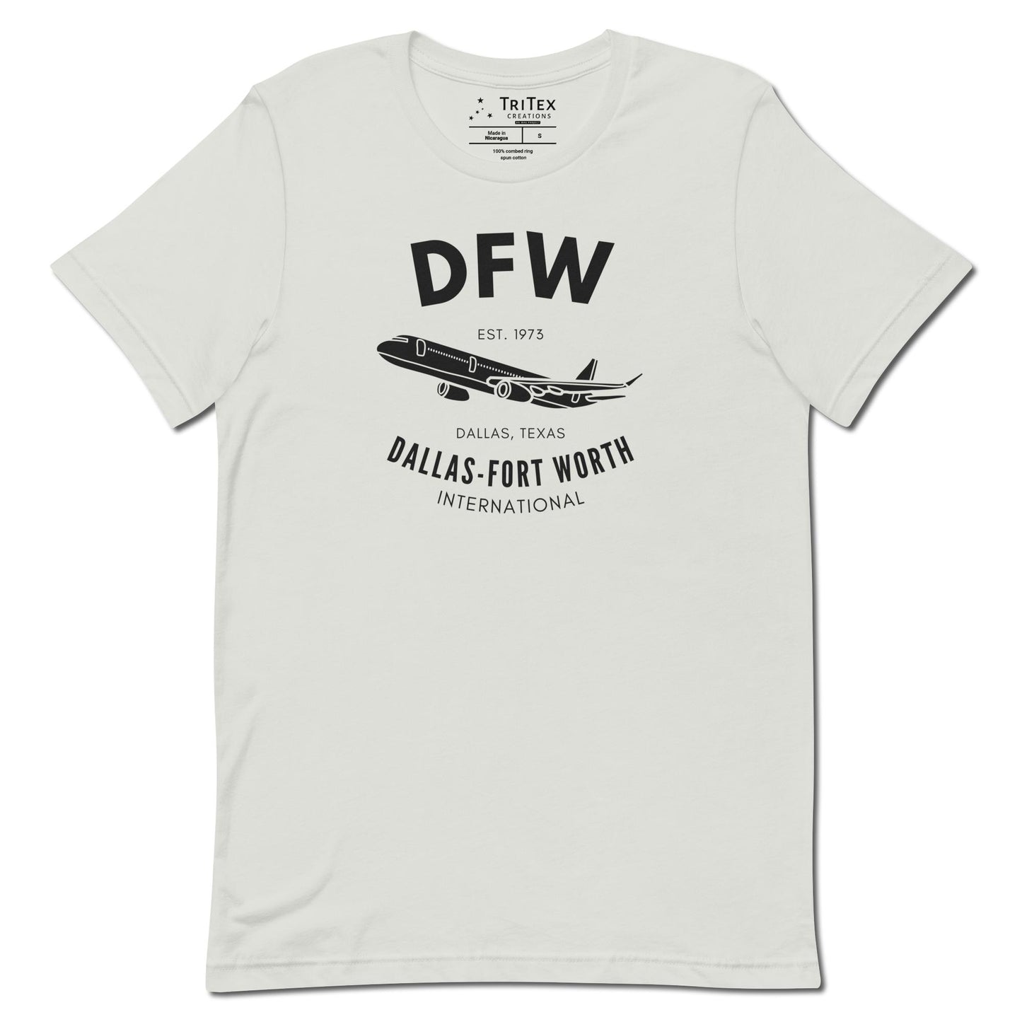 A silver t-shirt featuring a silhouette of a passenger plane with the text "DFW. Est. 1973. Dallas, Texas. Dallas-Fort Worth International".