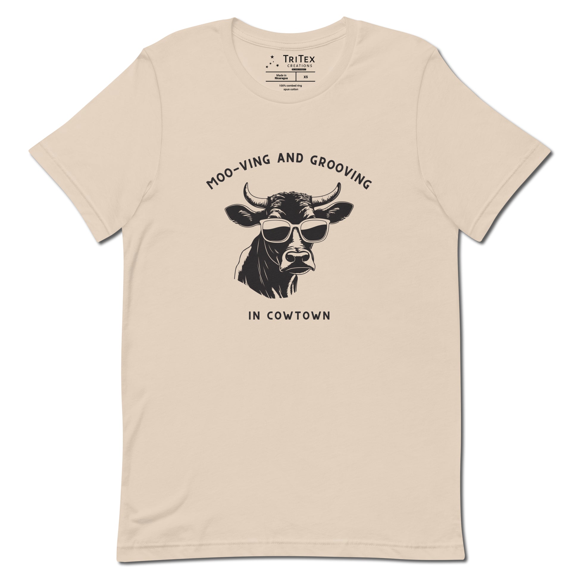 A soft cream t-shirt featuring an illustration of a cow wearing sunglasses with the the text "Moo-vin' n' groovin' in Cowtown".