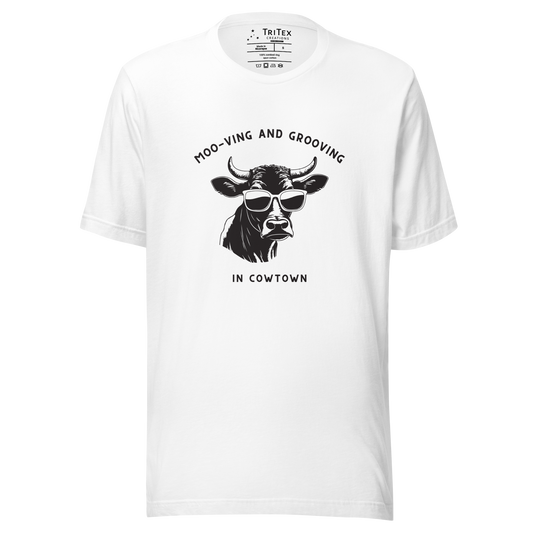 A white t-shirt featuring an illustration of a cow wearing sunglasses with the the text "Moo-vin' n' groovin' in Cowtown".